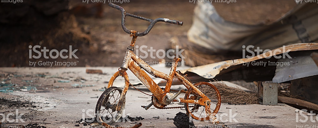 Child's bike against fire ravaged background