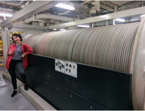 large spool of thick cable with woman leaning on spool