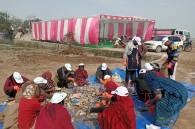 Group of people in India sorting plastic on a mat