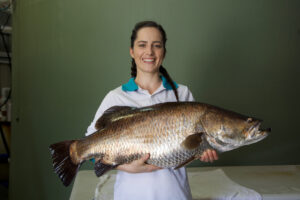 A young women holding a large fish.