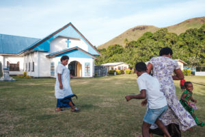 Kids and parents playing outside on the grass in front of a church in Fiji