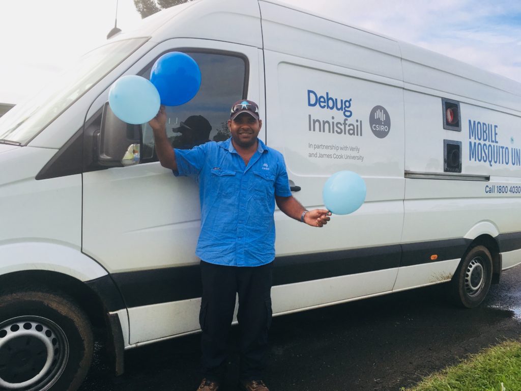 A man holds balloons in front of a white van with the logo Debug Innisfail.