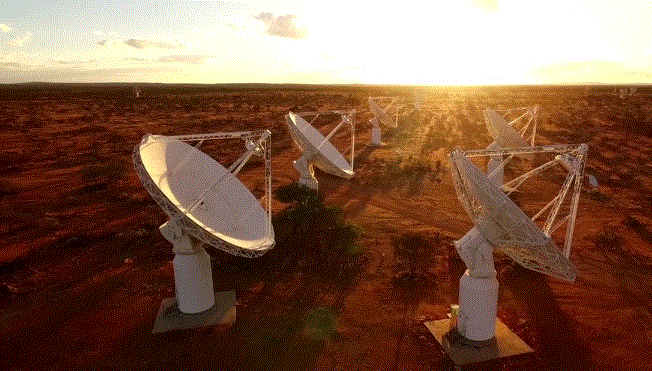 several large white telescope dishes in the desert