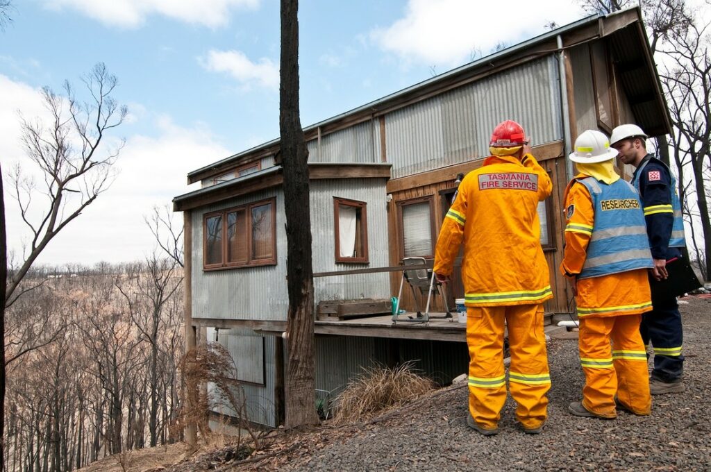 A photo of three people discussing fire damage to a house.