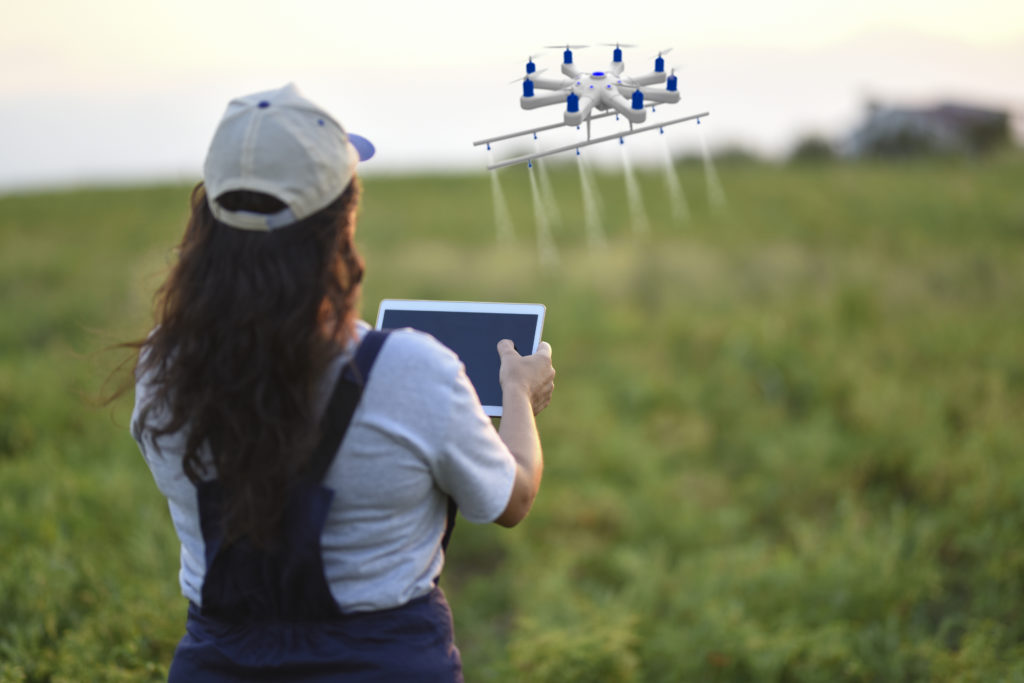 Young female farmer spraying her crops using a drone