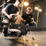 6 legged robot learning to walk, while researchers observe its walking pattern