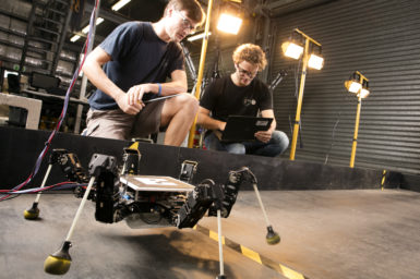 6 legged robot learning to walk, while researchers observe its walking pattern