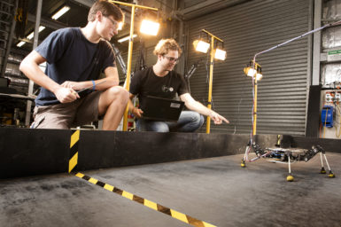 6 legged robot learning to walk, while researchers observe its walking pattern