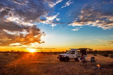 A track camped in a field at sunrise