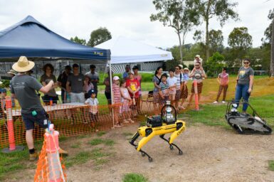 Staff show two robots to a group of visitors
