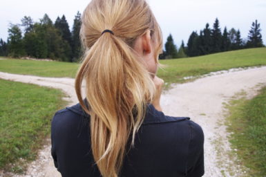 The back of a female head. She is trying to decide which of two paths to follow.