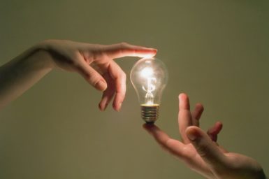 Lightbulb held between the index fingers of two hands