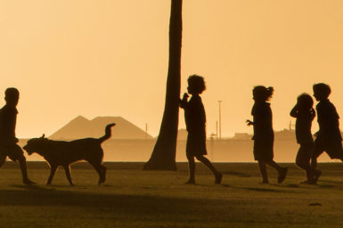 Children playing on the foreshore of an industrial port in the sunset.