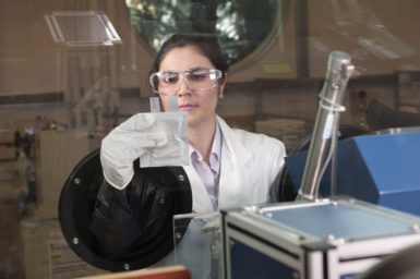 A researcher holds up a sachet inside a clean box.