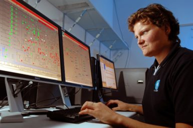 A person looks at diagrams on computer monitors