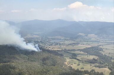 Smoke rising from a bushfire with township in the background.