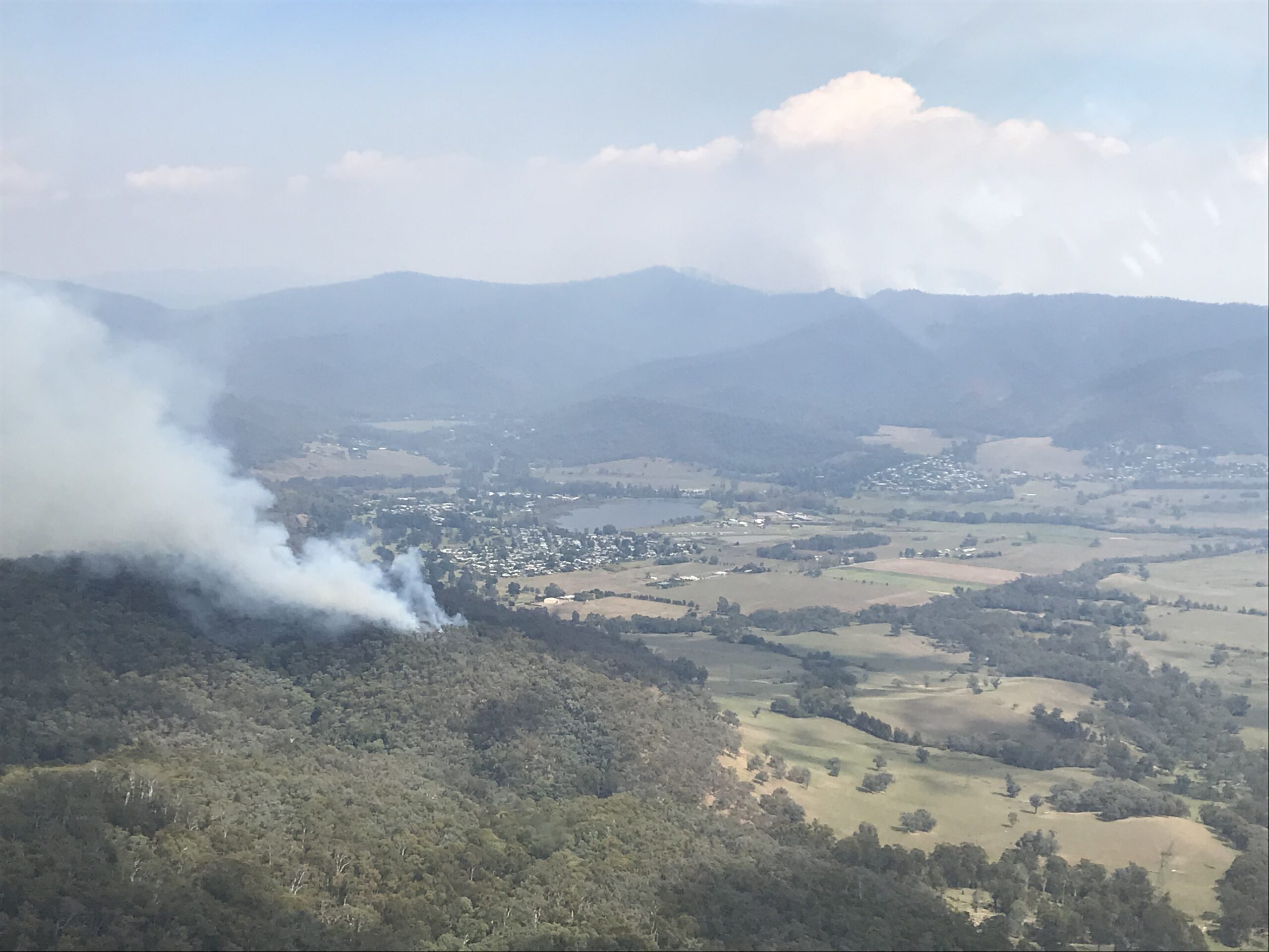 Smoke rising from a bushfire with township in the background.